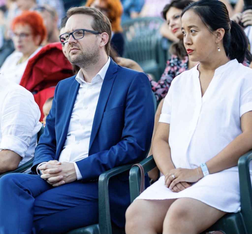 Dominic Fritz și soția sa, Yiran Lin, așezați împreună la un eveniment public în aer liber