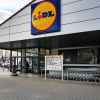 Magazin Lidl cu sigla oficială la intrare, panou de oferte promoționale și cărucioare
