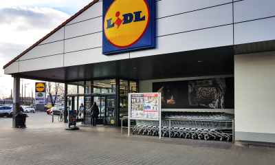 Magazin Lidl cu sigla oficială la intrare, panou de oferte promoționale și cărucioare