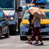 Pietoni protejați de umbrelă împotriva soarelui și a caniculei pe trecerea de pietoni