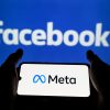 Smartphone cu sigla companiei Meta pe fundalul ecranului cu logo-ul Facebook