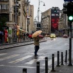 Oameni cu umbrele pe o stradă din București într-o zi ploioasă de toamnă