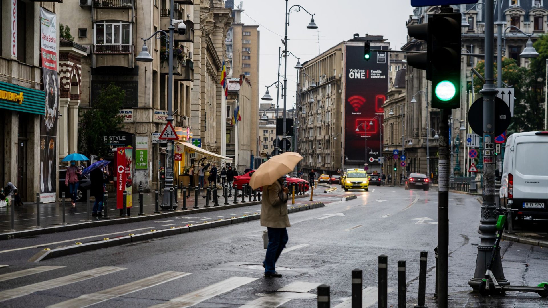Oameni cu umbrele pe o stradă din București într-o zi ploioasă de toamnă