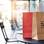 Pungi de cumpărături din hârtie cu inscripția Black Friday, pe o masă, reduceri 2026 în magazinele din România