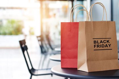 Pungi de cumpărături din hârtie cu inscripția Black Friday, pe o masă, reduceri 2026 în magazinele din România