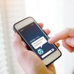 Mâini care țin un telefon cu o aplicație de chat cu inteligență artificială deschisă pe ecran
