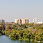 Stradă cu frunze căzute și oameni îmbrăcați gros într-o dimineață rece de toamnă târzie